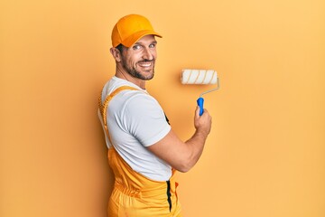Young caucasian painter smiling happy painting wall using roller.