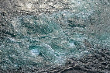 Abstract background. The waves of the sea water meet with underwater pointed rocks, forming...