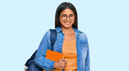 Young latin girl wearing student backpack and holding books with a happy and cool smile on face. lucky person.