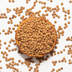 Raw brown lentil in a wooden bowl isolated on white background 