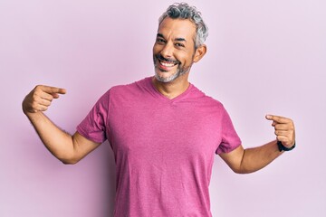 Middle age grey-haired man wearing casual clothes looking confident with smile on face, pointing...