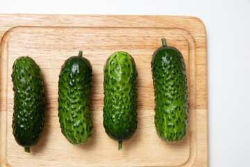 Group of green short cucumbers. Whole cucumbers on cutting board. Preparation ingredients for cooking or pickling.