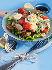 Salad with mussels, tomatoes, eggs, arugula, spinach, lemon and croutons on blue background. Seafood salad with vine sauce