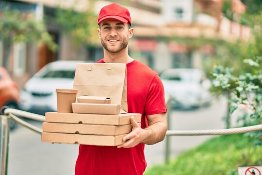 Young caucasian deliveryman smiling happy holding delivery food at the city.