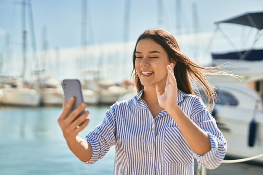 Young hispanic girl smiling happy doing video call using smartphone at the port