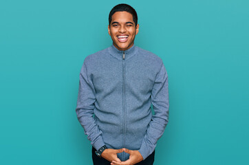 Young handsome hispanic man wearing casual sweatshirt winking looking at the camera with sexy...