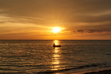 Cuba. Trinidad. Sunset in Ancon. A fisherman on a boat crosses the Sunny path