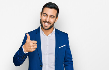 Young hispanic man wearing business jacket doing happy thumbs up gesture with hand. approving expression looking at the camera showing success.