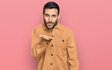 Young hispanic man wearing casual clothes looking at the camera blowing a kiss with hand on air being lovely and sexy. love expression.