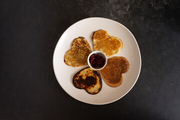 Pancakes on a round white plate with jam. On a black background.