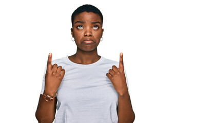 Young african american woman wearing casual white t shirt pointing up looking sad and upset,...