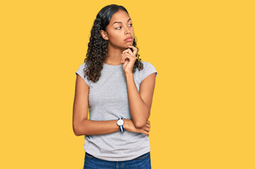 Young african american girl wearing casual clothes with hand on chin thinking about question, pensive expression. smiling with thoughtful face. doubt concept.