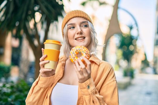 Young blonde girl smiling happy having breakfast at the city.