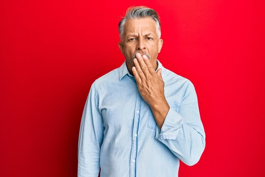 Middle age grey-haired man wearing casual clothes bored yawning tired covering mouth with hand. restless and sleepiness.