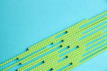 disposable green and white straws are laid out on a background of blue