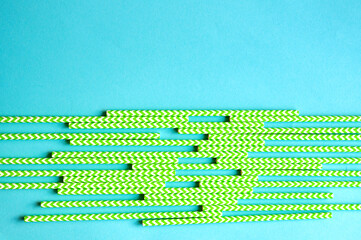 disposable green and white straws are laid out on a background of blue
