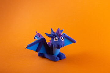Blue indigo clay dragon with wings and squama on orange background. Modelling clay, playing dough...