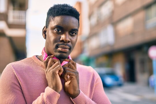 Young african american man with serious expression using headphones at the city.