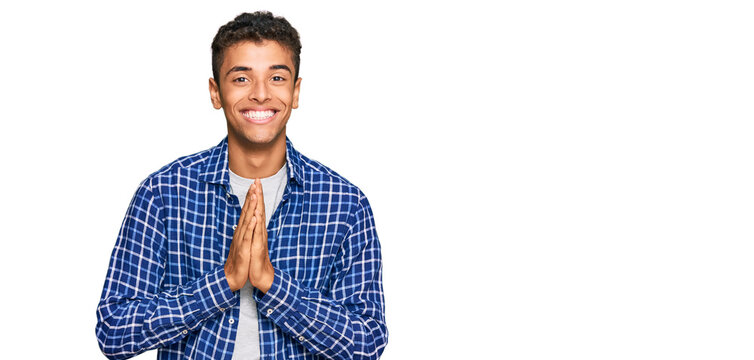 Young handsome african american man wearing casual clothes praying with hands together asking for forgiveness smiling confident.