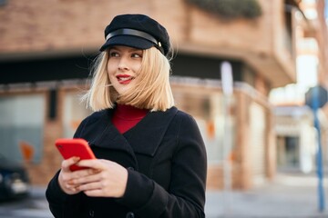 Obraz premium Young blonde woman smiling happy using smartphone at the city.