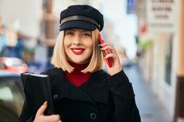 Young blonde woman smiling happy talking on the smartphone at the city.