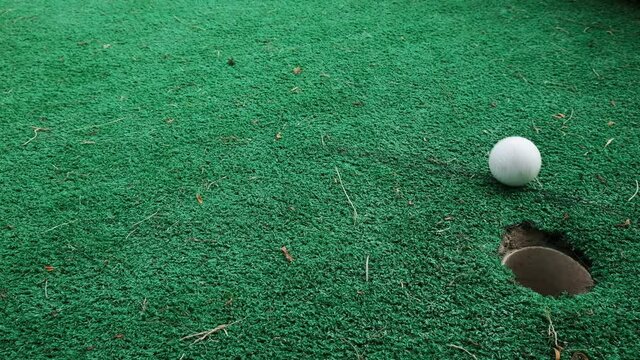 Almost there, don't stop before you achieve a goal. So close to winning, last failure on the road to success. Mini golf on green lawn outside, missed shot, another mistake before succeeding in life.