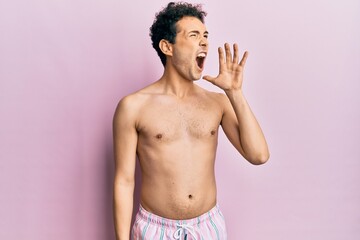 Fototapeta premium Young handsome man wearing swimwear shirtless shouting and screaming loud to side with hand on mouth. communication concept.