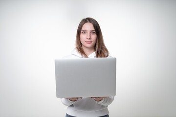 Naklejka premium Young cute woman is holding an opened laptop with both hands, studio photo on white background
