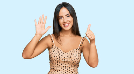 Young beautiful hispanic girl wearing sexy party dress showing and pointing up with fingers number six while smiling confident and happy.