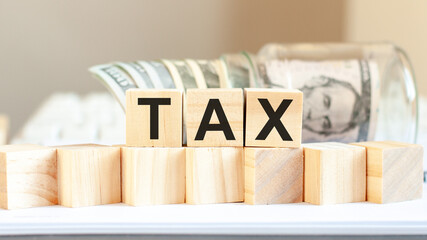 Tax word written on wooden blocks. American currency. Money and financial concept.