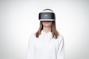 Studio portrait of a girl with long fair hair, seriously testing VR headset on white background
