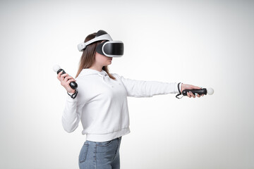 Side view of a sexy young woman with good figure, playing motion sticks and VR glasses, white studio background