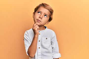 Adorable latin kid wearing casual clothes thinking concentrated about doubt with finger on chin and...