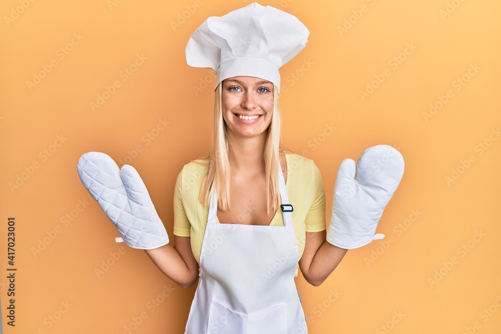 Poster Young blonde girl wearing baker uniform and cook hat smiling with a happy and cool smile on face. showing teeth.