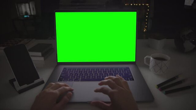Female hands scrolling on a track pad. Laptop with green screen.  Dark office. Locked. Perfect to put your own image or video. Track with perspective corner pin.  