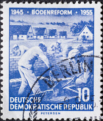  some construction workers are building the new house with bricks. In the background houses of a...