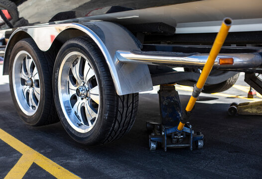 Close up view of a car jack lifting up a boat trailer that just had a new tire installed. Need new tires?