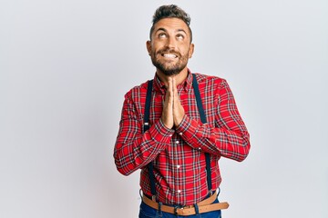 Handsome man with beard wearing hipster elegant look begging and praying with hands together with...