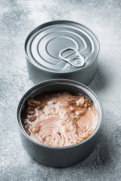 Tuna in a can, whole and chopped, in tin can, on gray background