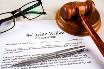 Living will declaration form with pen, gavel and striking block and glasses on top.