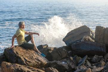 Man meditating on rock in beach coast