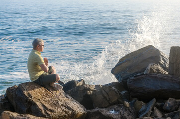 Fototapeta na wymiar Man meditating on rock in beach coast