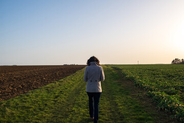Girl with a coat between two field at dawn