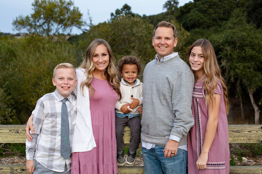 Smiling and happy diverse group with a mixed race adopted baby boy and two other children. Attractive people standing together