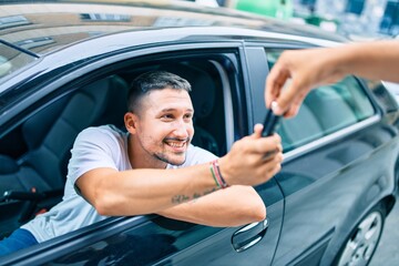 Young hispanic man smiling happy holding key of new car