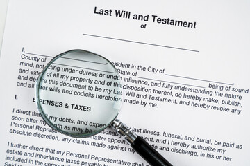Last will and testament document form and magnifying glass.