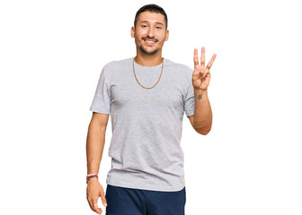 Fototapeta premium Handsome man with tattoos wearing 90s style showing and pointing up with fingers number three while smiling confident and happy.