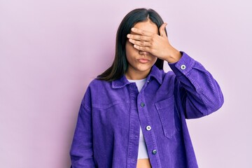 Young brunette woman wearing casual clothes covering eyes with hand, looking serious and sad. sightless, hiding and rejection concept