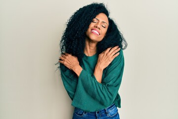 Middle age african american woman wearing casual clothes hugging oneself happy and positive, smiling confident. self love and self care