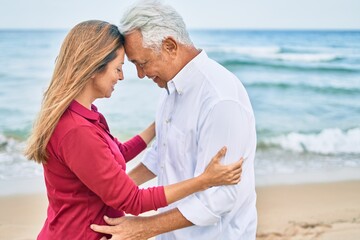 Fototapeta premium Middle age hispanic couple smiling happy and hugging walking at the beach